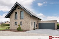 Szara cegła na elewacji, dom z szarej cegły, projekty elewacji z cegły, dom ze spadzistym dachem, grafitowe okna, dom z dużą bramą garażową,